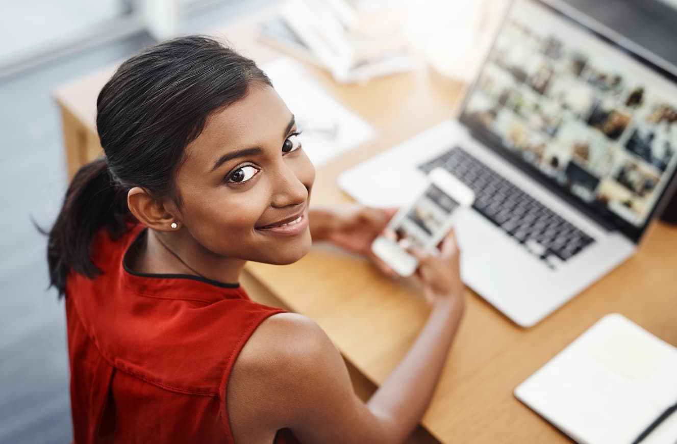 Young professional using a smartphone and laptop, showcasing the importance of a digital presence for businesses in 2025.